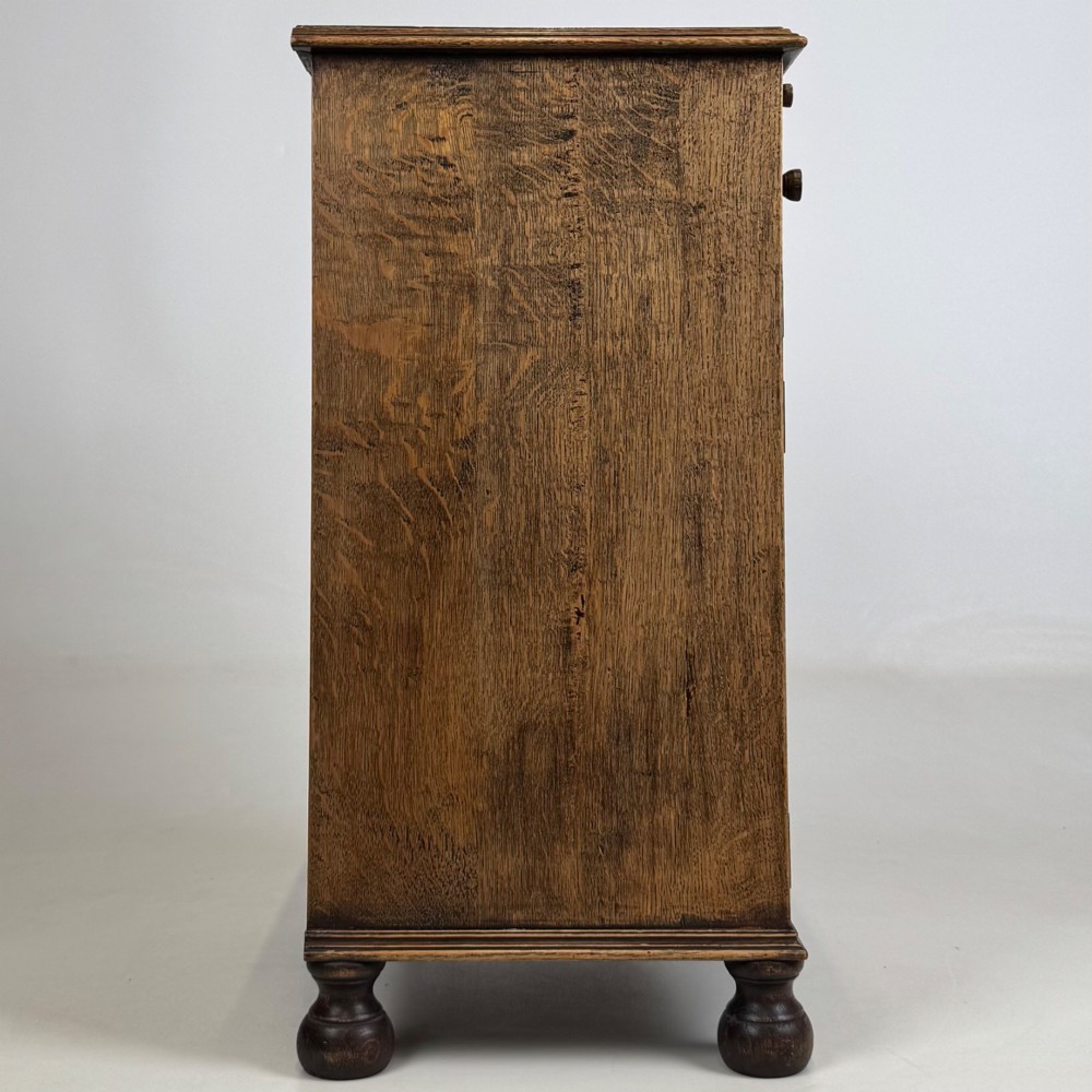 A small Edwardian carved dark oak cabinet with a single top drawer, a lower cupboard door, turned wooden knobs, and bun feet. View VIII