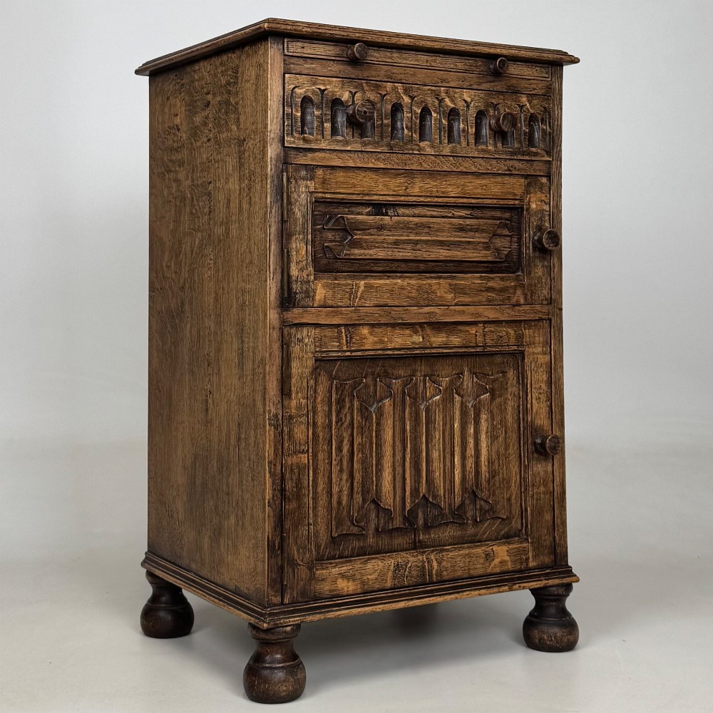 A small Edwardian carved dark oak cabinet with a single top drawer, a lower cupboard door, turned wooden knobs, and bun feet. View IX