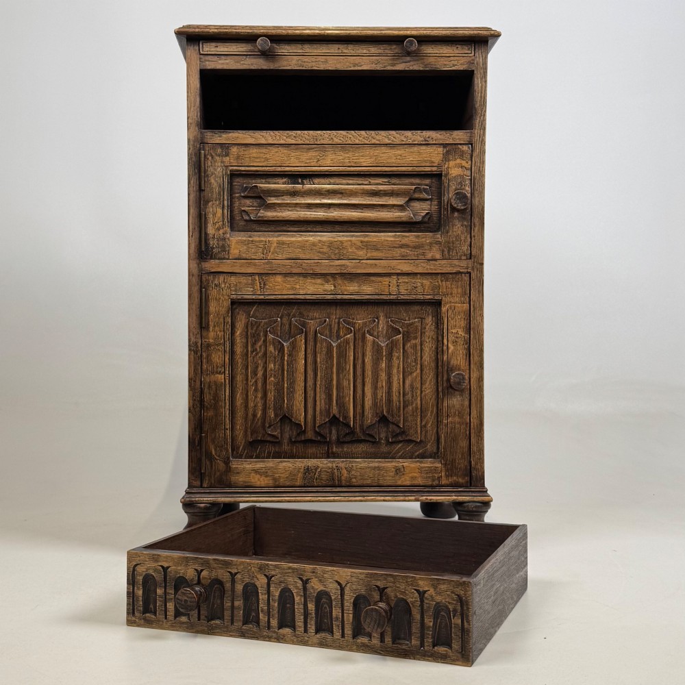 A small Edwardian carved dark oak cabinet with a single top drawer, a lower cupboard door, turned wooden knobs, and bun feet. View XII