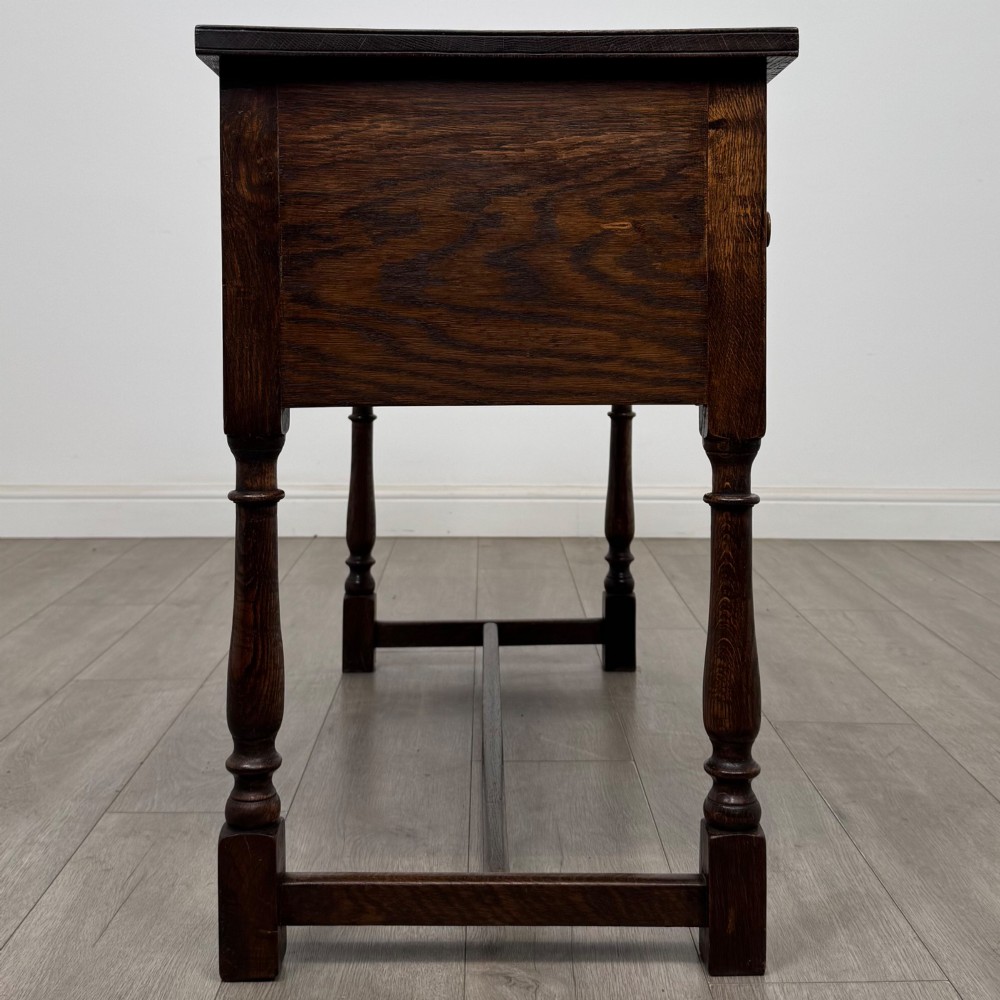 An Edwardian oak writing desk featuring three drawers with geometric carved fronts, turned legs, and a lower stretcher base. View VII