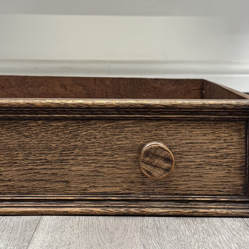 An Edwardian oak writing desk featuring three drawers with geometric carved fronts, turned legs, and a lower stretcher base. View XI