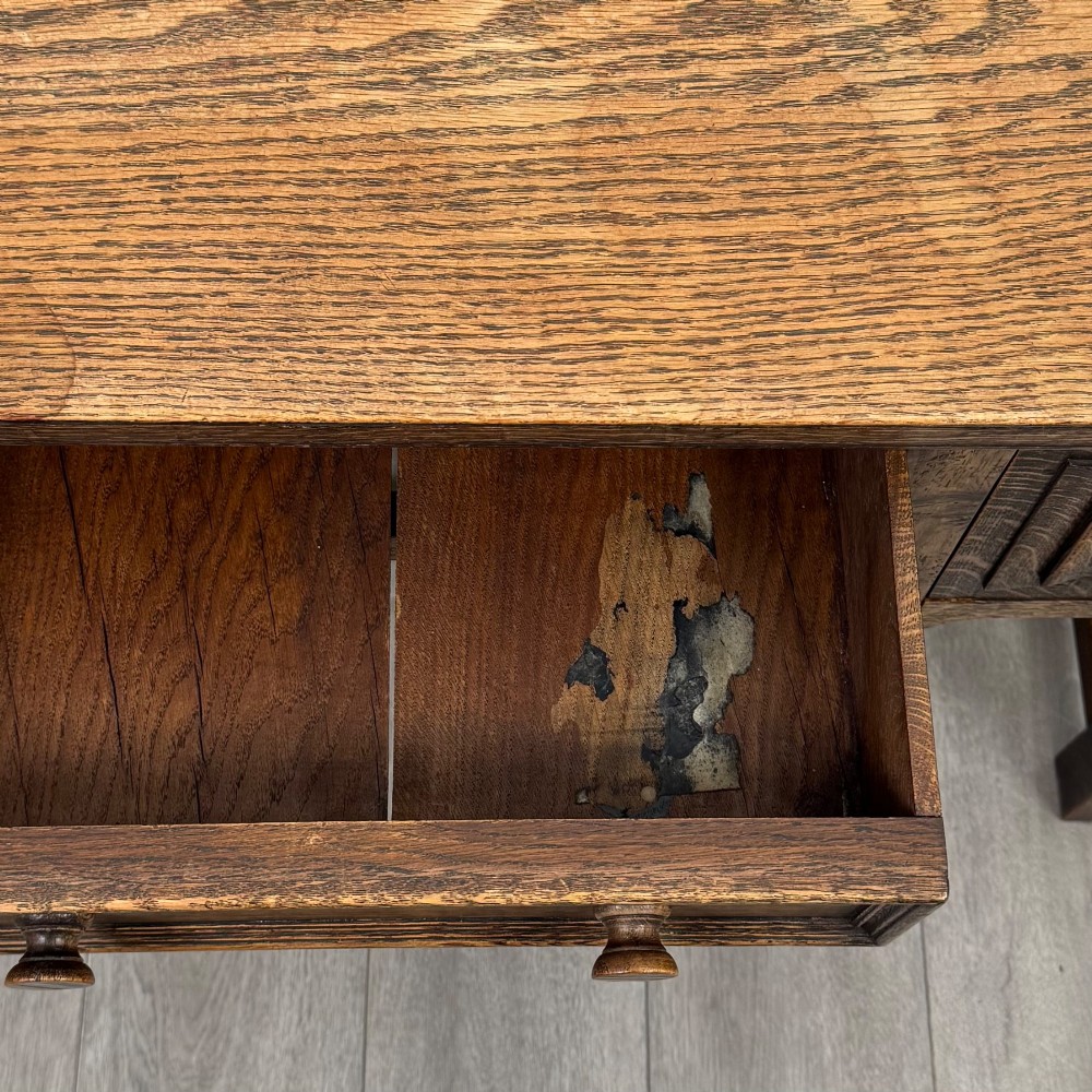 An Edwardian oak writing desk featuring three drawers with geometric carved fronts, turned legs, and a lower stretcher base. View XII