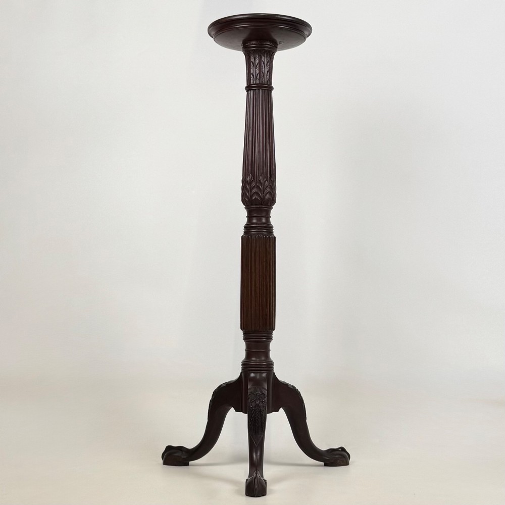 A tall Victorian dark mahogany plant stand featuring a carved fluted column, acanthus leaf details, and a tripod base.