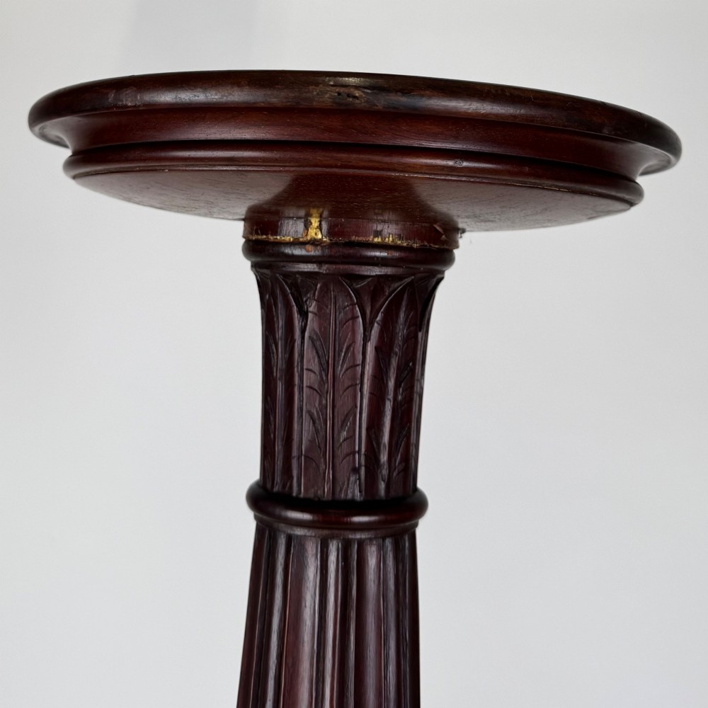 A tall Victorian dark mahogany plant stand featuring a carved fluted column, acanthus leaf details, and a tripod base. View VI