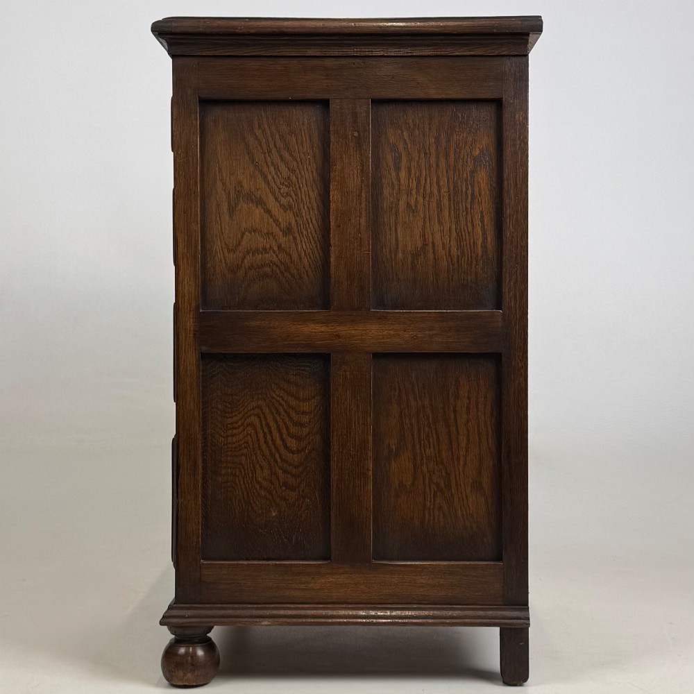 A small dark oak Edwardian chest featuring four drawers with brass drop handles and turned bun feet. View III