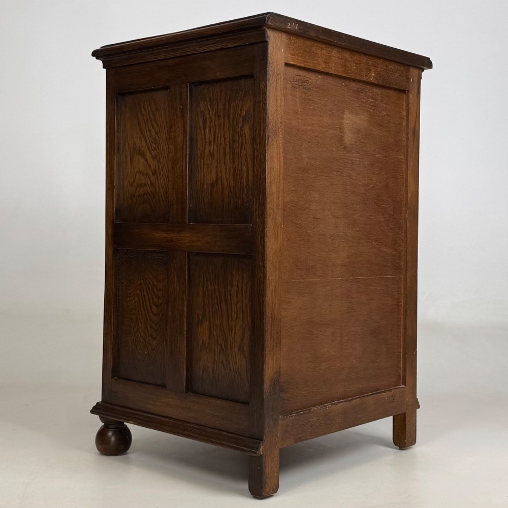 A small dark oak Edwardian chest featuring four drawers with brass drop handles and turned bun feet. View IV
