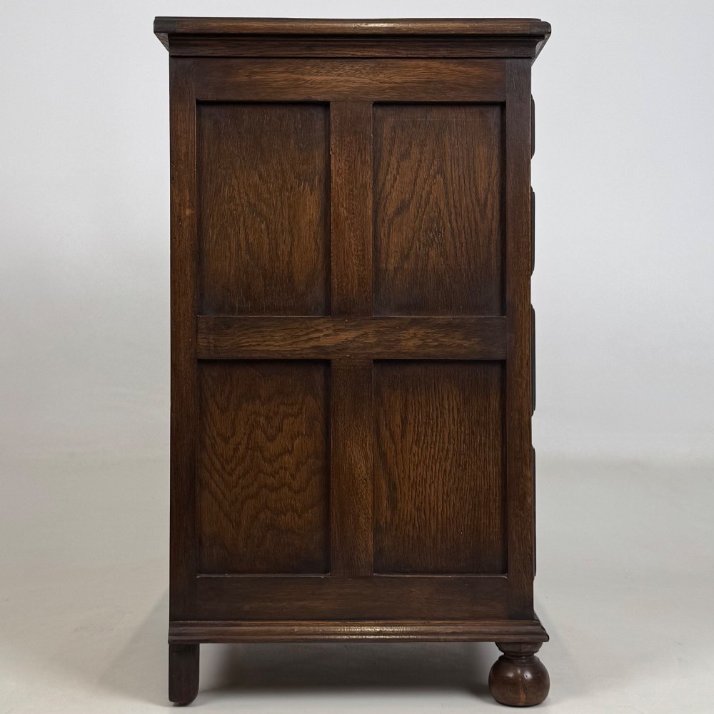 A small dark oak Edwardian chest featuring four drawers with brass drop handles and turned bun feet. View VII