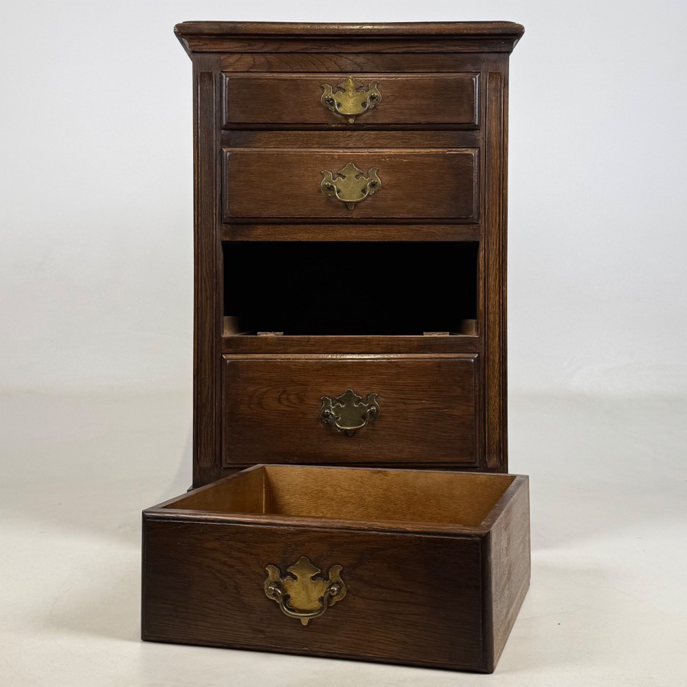 A small dark oak Edwardian chest featuring four drawers with brass drop handles and turned bun feet. View IX