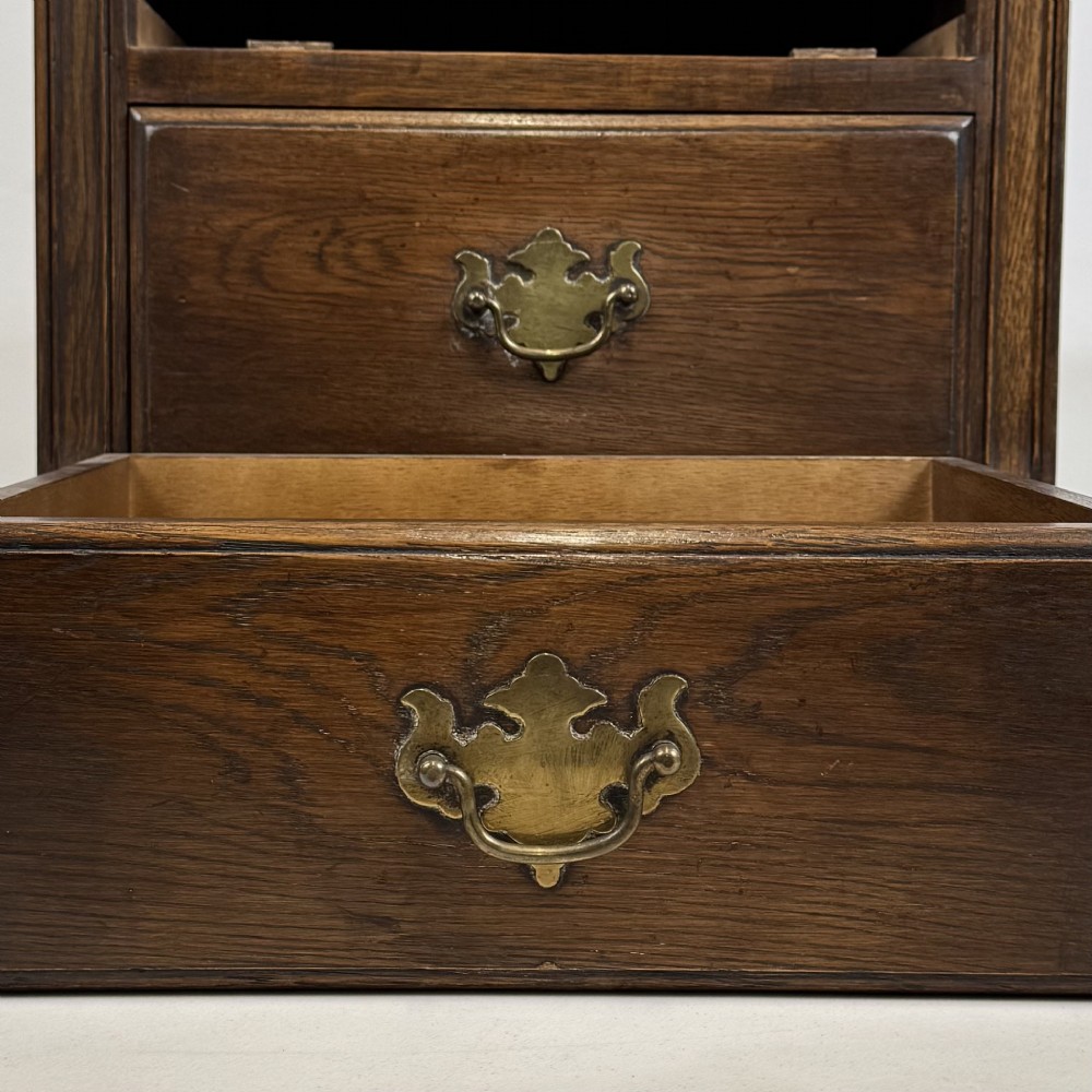 A small dark oak Edwardian chest featuring four drawers with brass drop handles and turned bun feet. View X