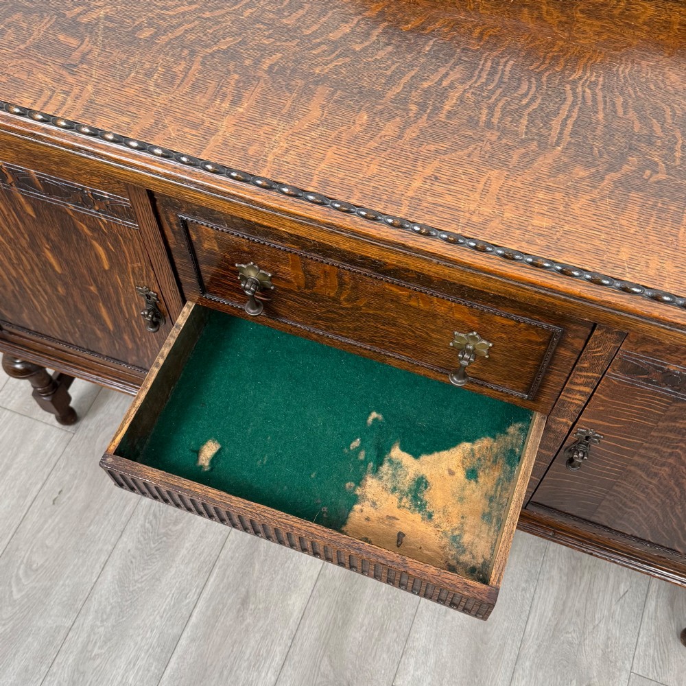 An Edwardian dark oak sideboard featuring two central drawers flanked by cupboard doors, raised on turned front legs with a low back gallery. View XIII