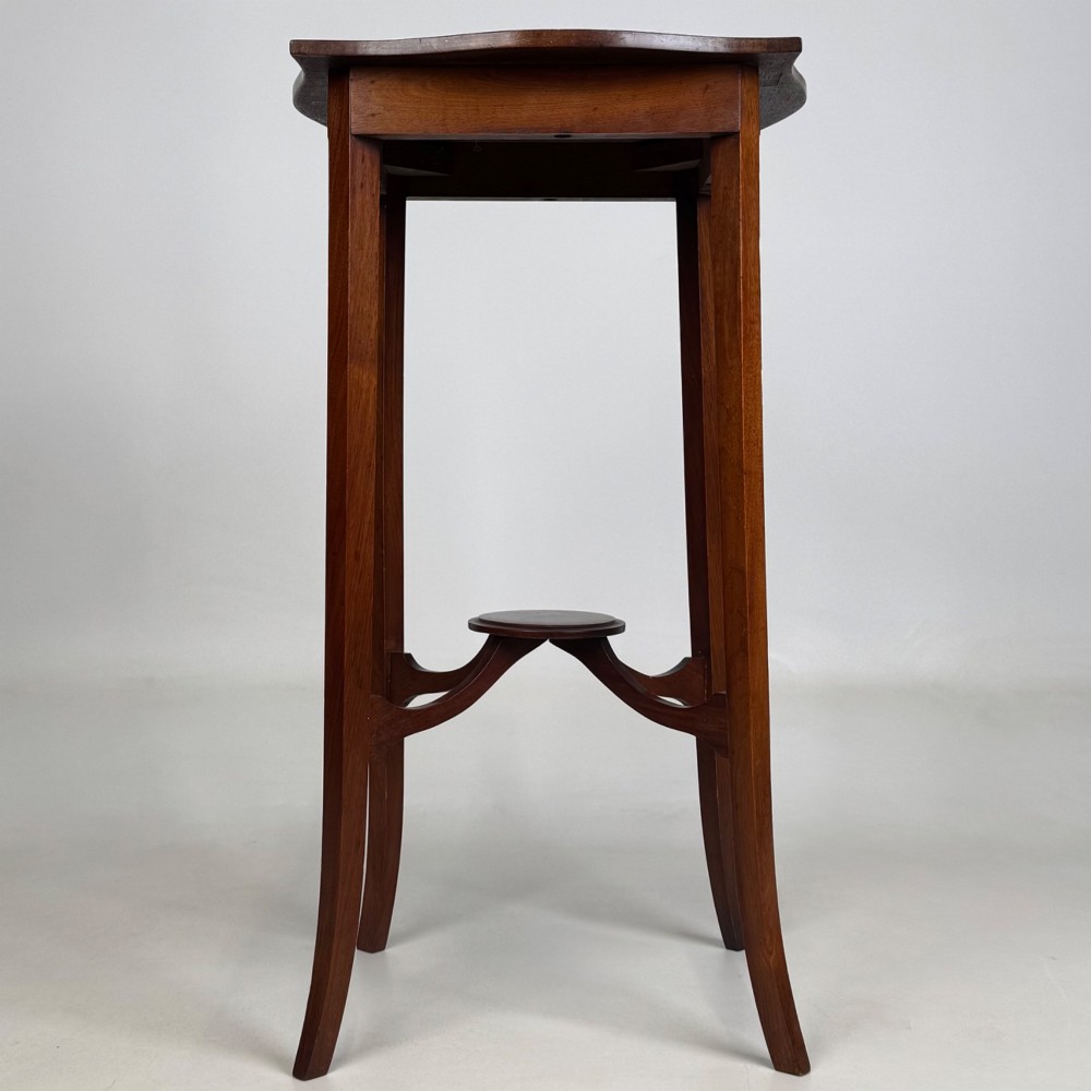 A tall Edwardian mahogany side table featuring a shaped top, slender splayed legs, and an arched stretcher tier. View III