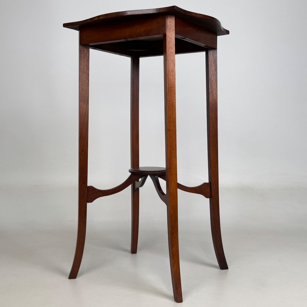 A tall Edwardian mahogany side table featuring a shaped top, slender splayed legs, and an arched stretcher tier. View IV
