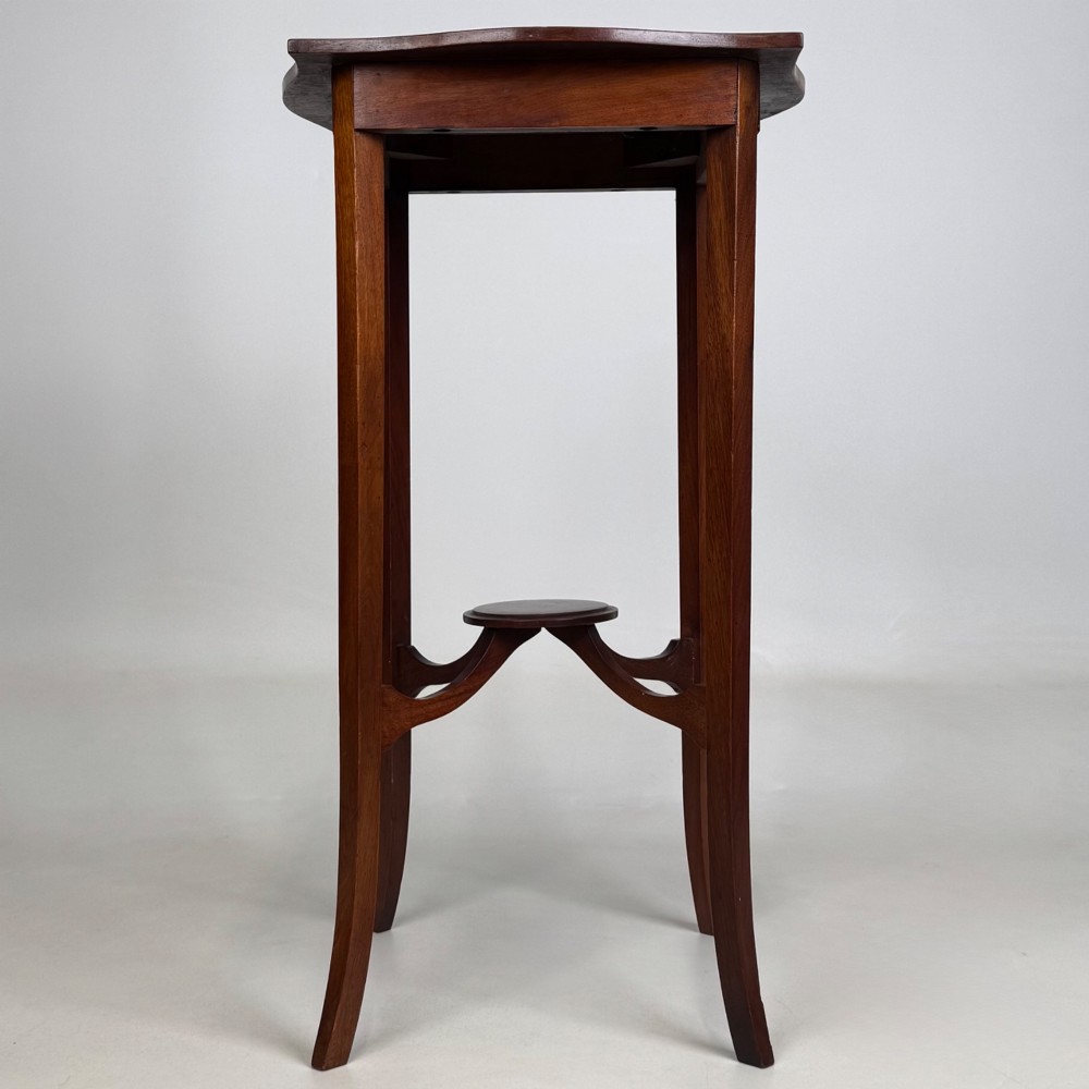 A tall Edwardian mahogany side table featuring a shaped top, slender splayed legs, and an arched stretcher tier. View V