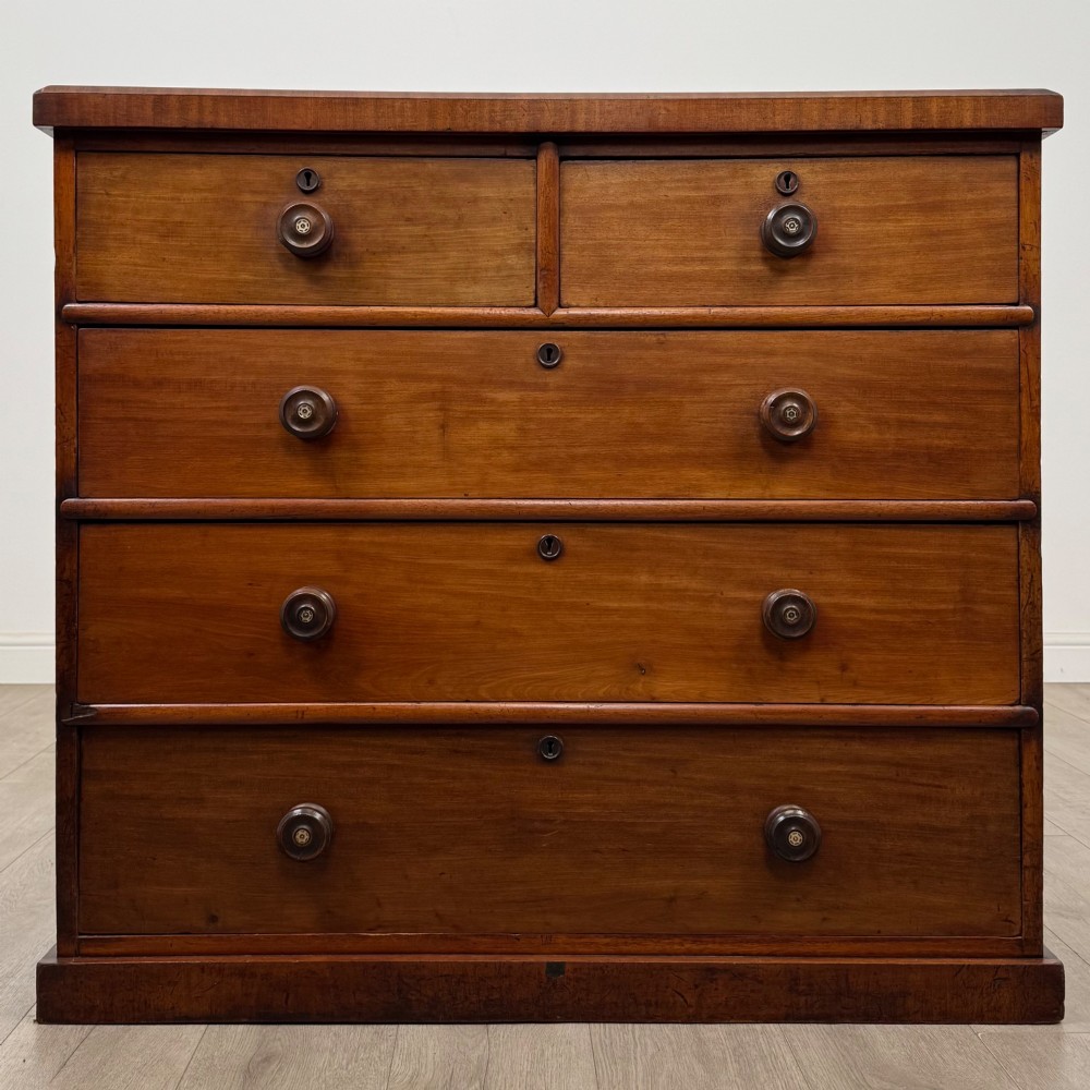 A nineteenth-century Victorian mahogany chest of drawers featuring a two over three drawer layout with turned wooden knobs and a plinth base.