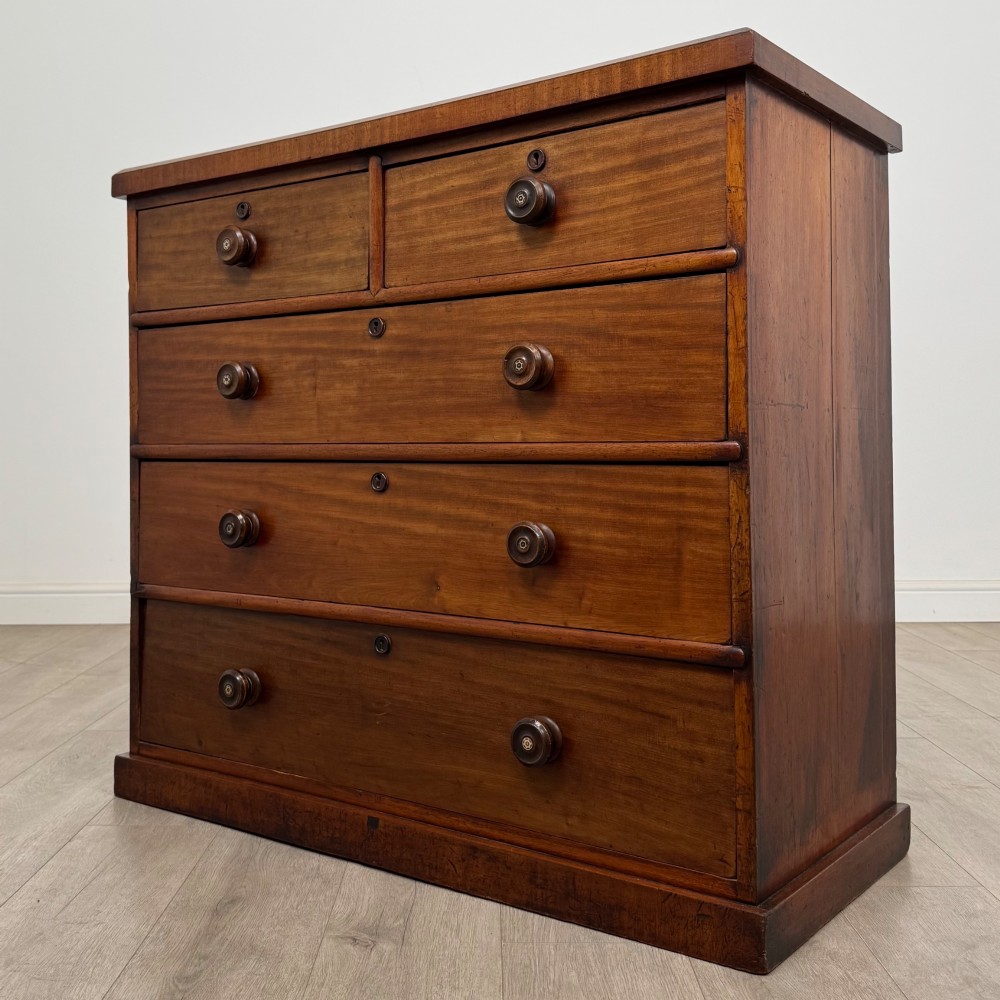 A nineteenth-century Victorian mahogany chest of drawers featuring a two over three drawer layout with turned wooden knobs and a plinth base. View II