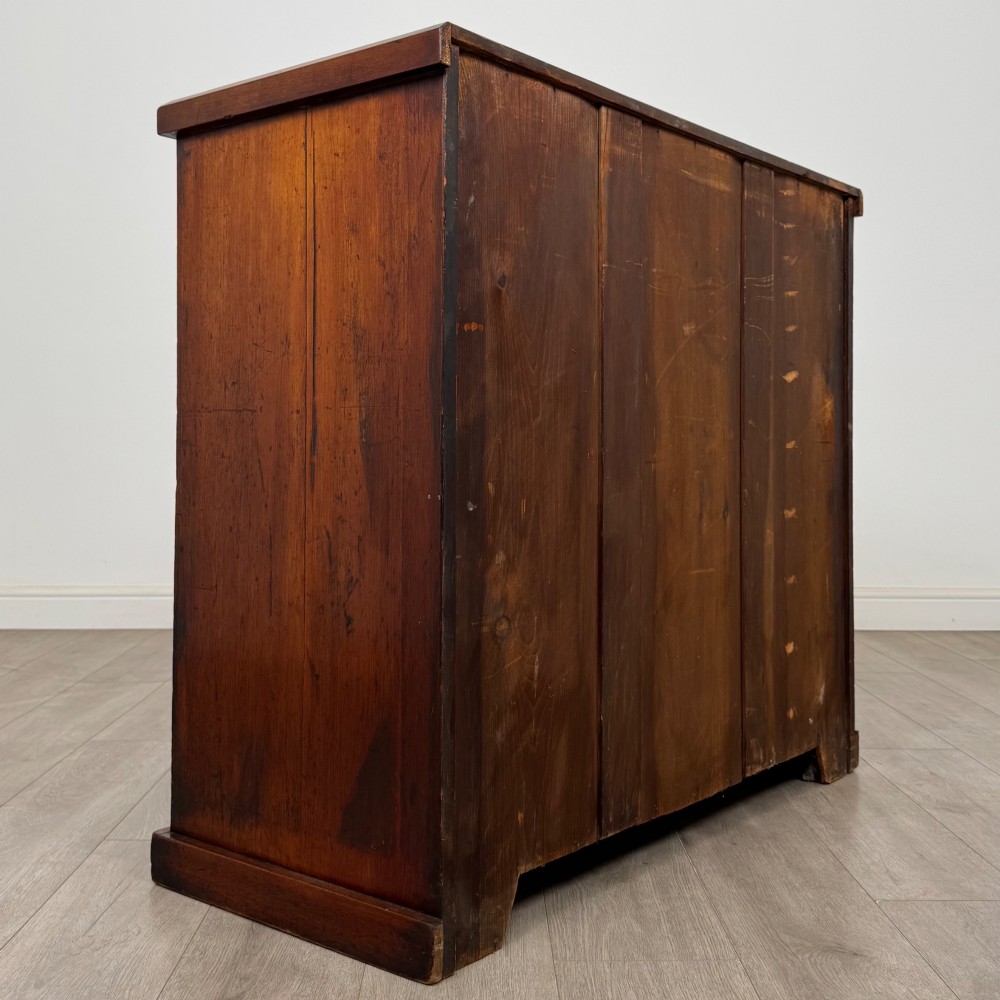 A nineteenth-century Victorian mahogany chest of drawers featuring a two over three drawer layout with turned wooden knobs and a plinth base. View IV