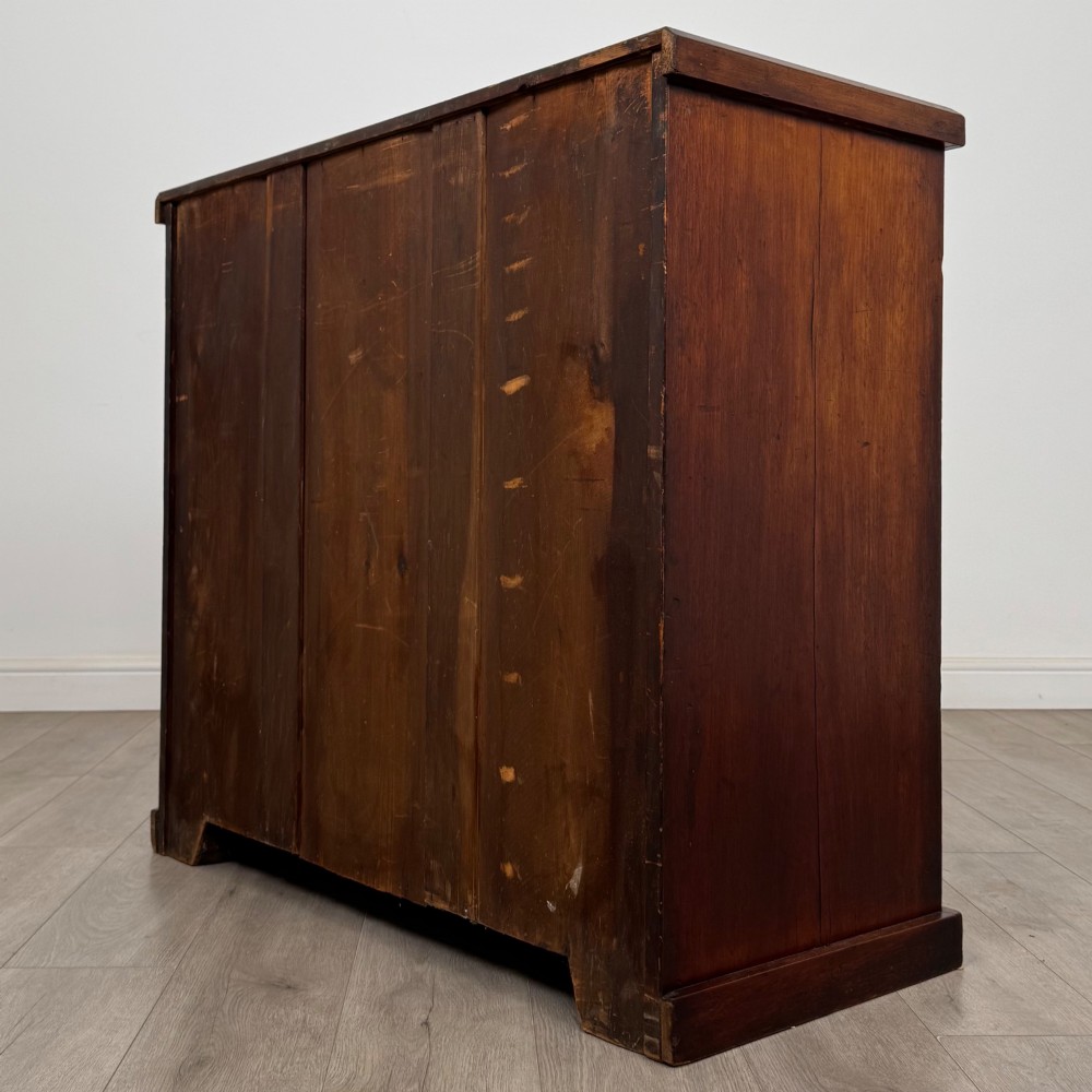 A nineteenth-century Victorian mahogany chest of drawers featuring a two over three drawer layout with turned wooden knobs and a plinth base. View VI