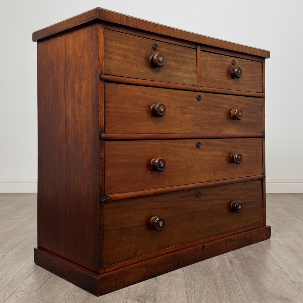 A nineteenth-century Victorian mahogany chest of drawers featuring a two over three drawer layout with turned wooden knobs and a plinth base. View VIII