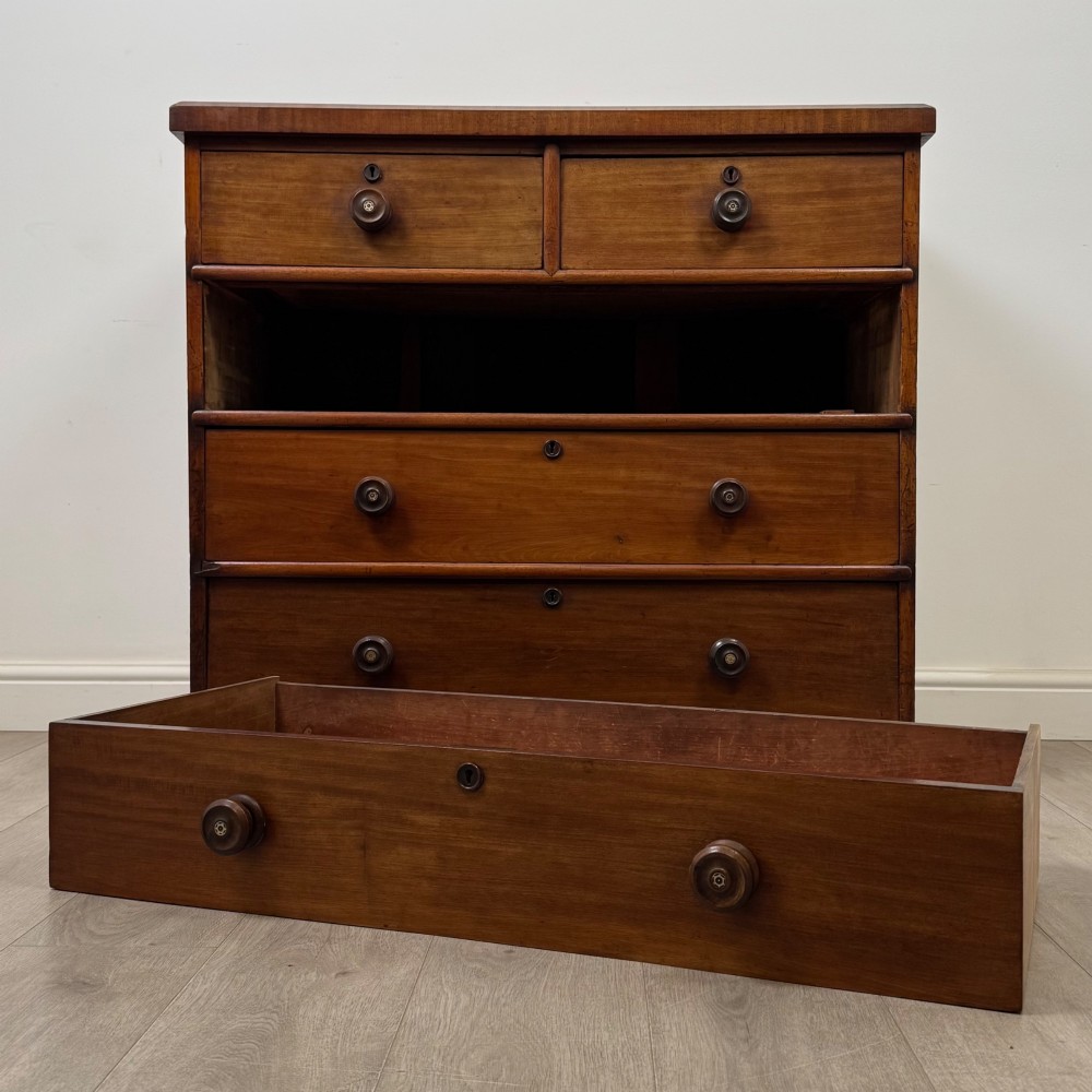 A nineteenth-century Victorian mahogany chest of drawers featuring a two over three drawer layout with turned wooden knobs and a plinth base. View X
