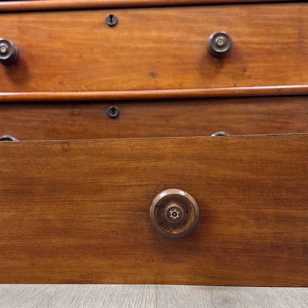 A nineteenth-century Victorian mahogany chest of drawers featuring a two over three drawer layout with turned wooden knobs and a plinth base. View XI