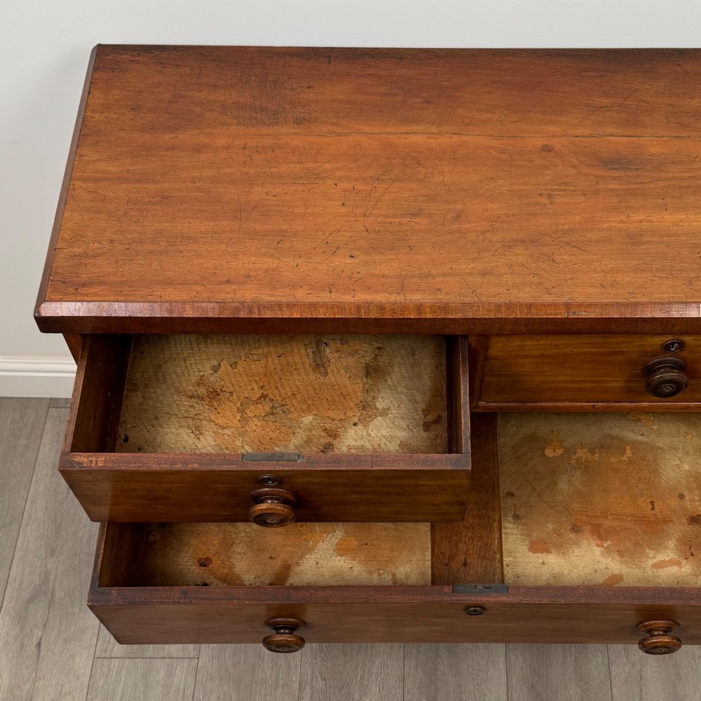 A nineteenth-century Victorian mahogany chest of drawers featuring a two over three drawer layout with turned wooden knobs and a plinth base. View XII