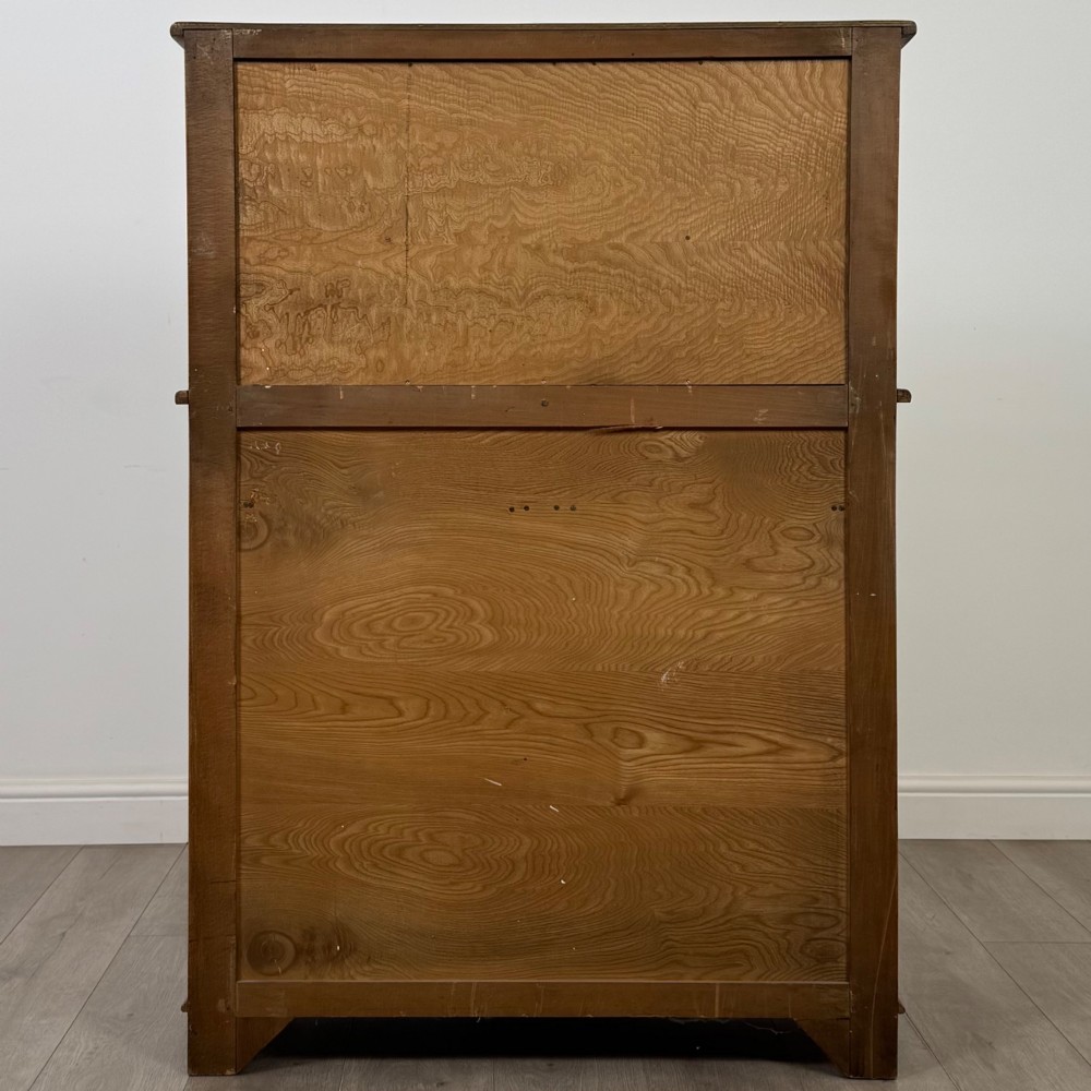 A twentieth-century golden oak court cupboard featuring carved panels, leaded glass side doors, and turned bulbous supports. View VI