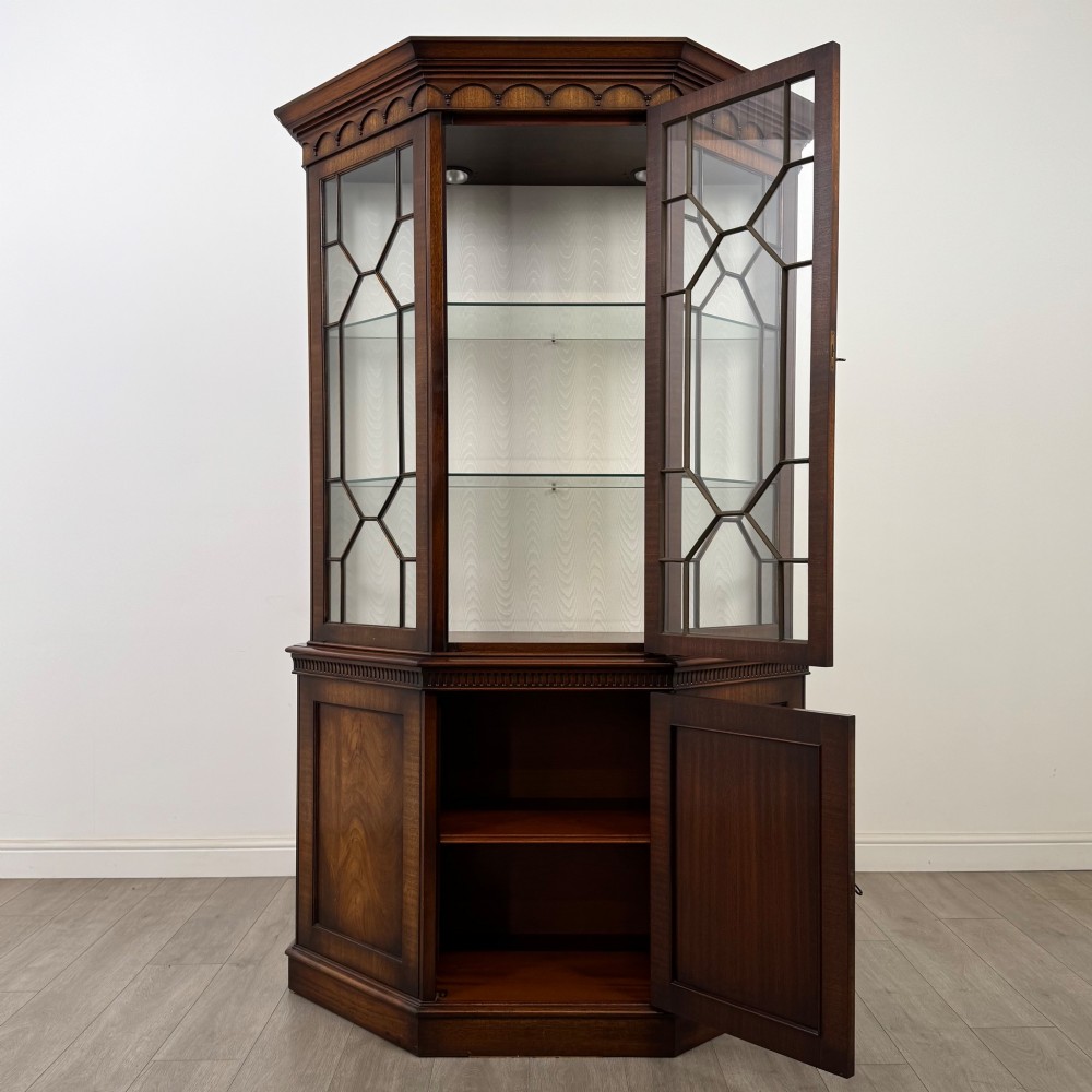 A tall mahogany display cabinet featuring astragal glazed upper doors, glass shelving, and flame mahogany lower panel doors with a canted front. View II
