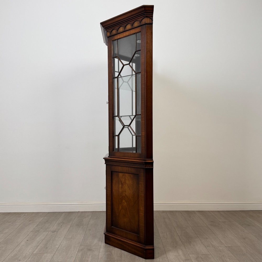 A tall mahogany display cabinet featuring astragal glazed upper doors, glass shelving, and flame mahogany lower panel doors with a canted front. View IV