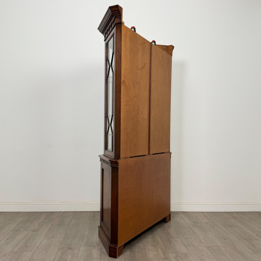 A tall mahogany display cabinet featuring astragal glazed upper doors, glass shelving, and flame mahogany lower panel doors with a canted front. View V