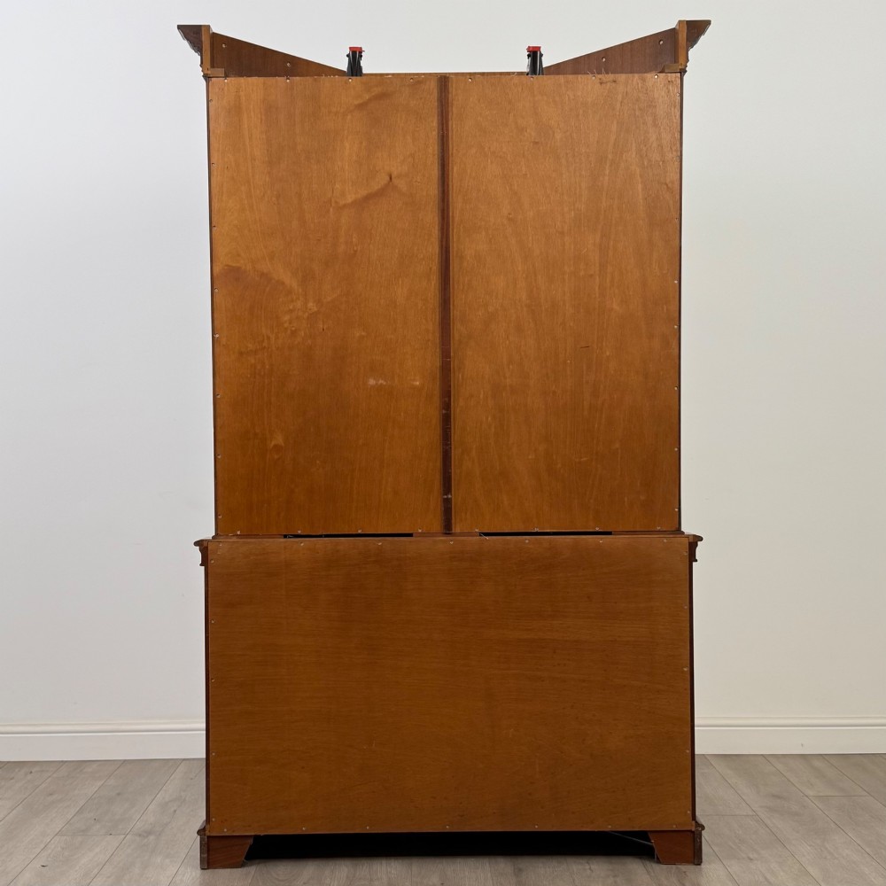 A tall mahogany display cabinet featuring astragal glazed upper doors, glass shelving, and flame mahogany lower panel doors with a canted front. View VI