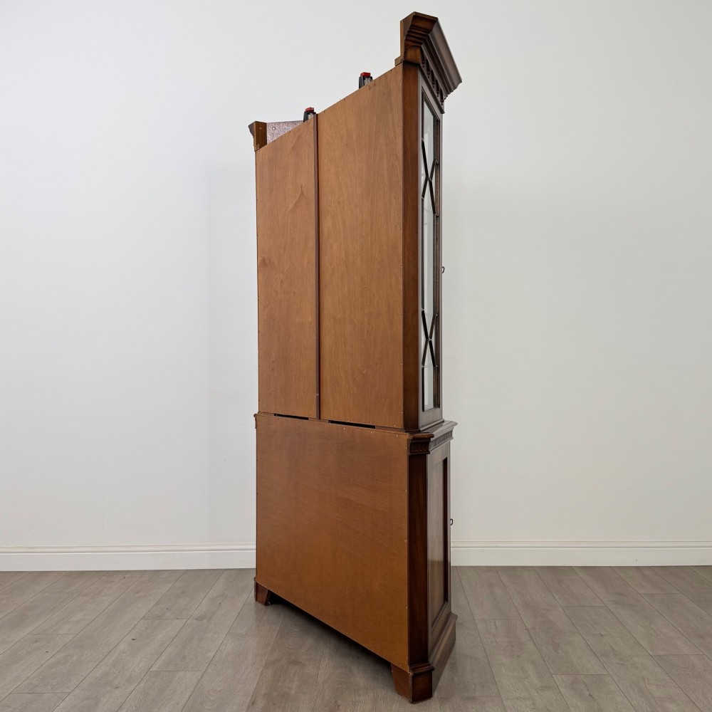 A tall mahogany display cabinet featuring astragal glazed upper doors, glass shelving, and flame mahogany lower panel doors with a canted front. View VII