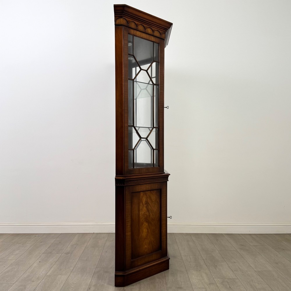 A tall mahogany display cabinet featuring astragal glazed upper doors, glass shelving, and flame mahogany lower panel doors with a canted front. View VIII
