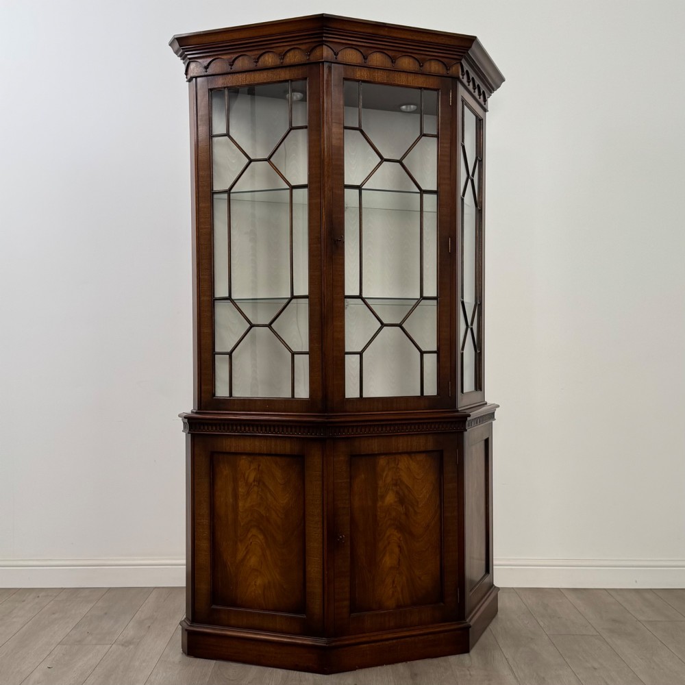 A tall mahogany display cabinet featuring astragal glazed upper doors, glass shelving, and flame mahogany lower panel doors with a canted front. View IX
