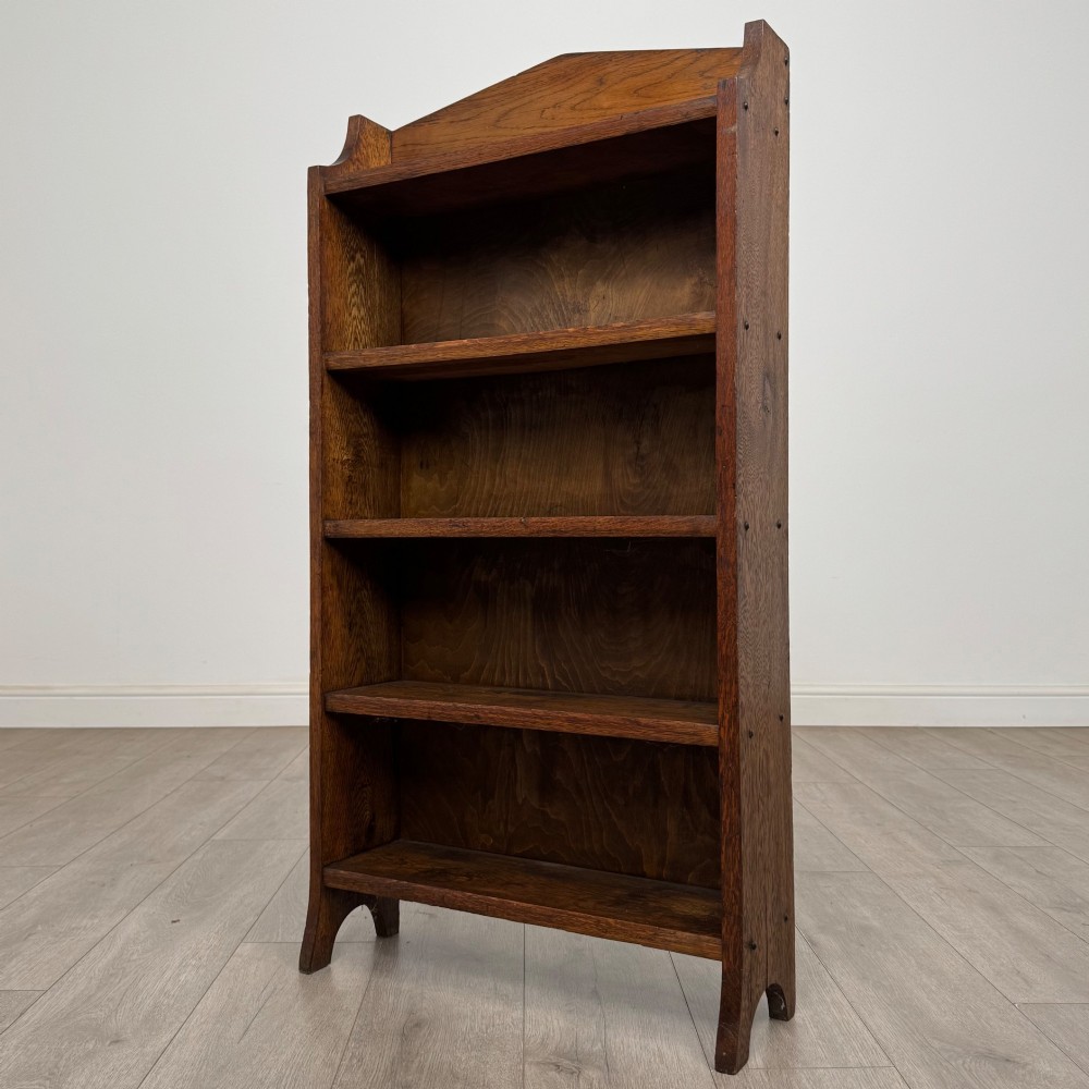 A freestanding Edwardian open oak bookcase featuring four tiers of shelves and a gabled top gallery. View III
