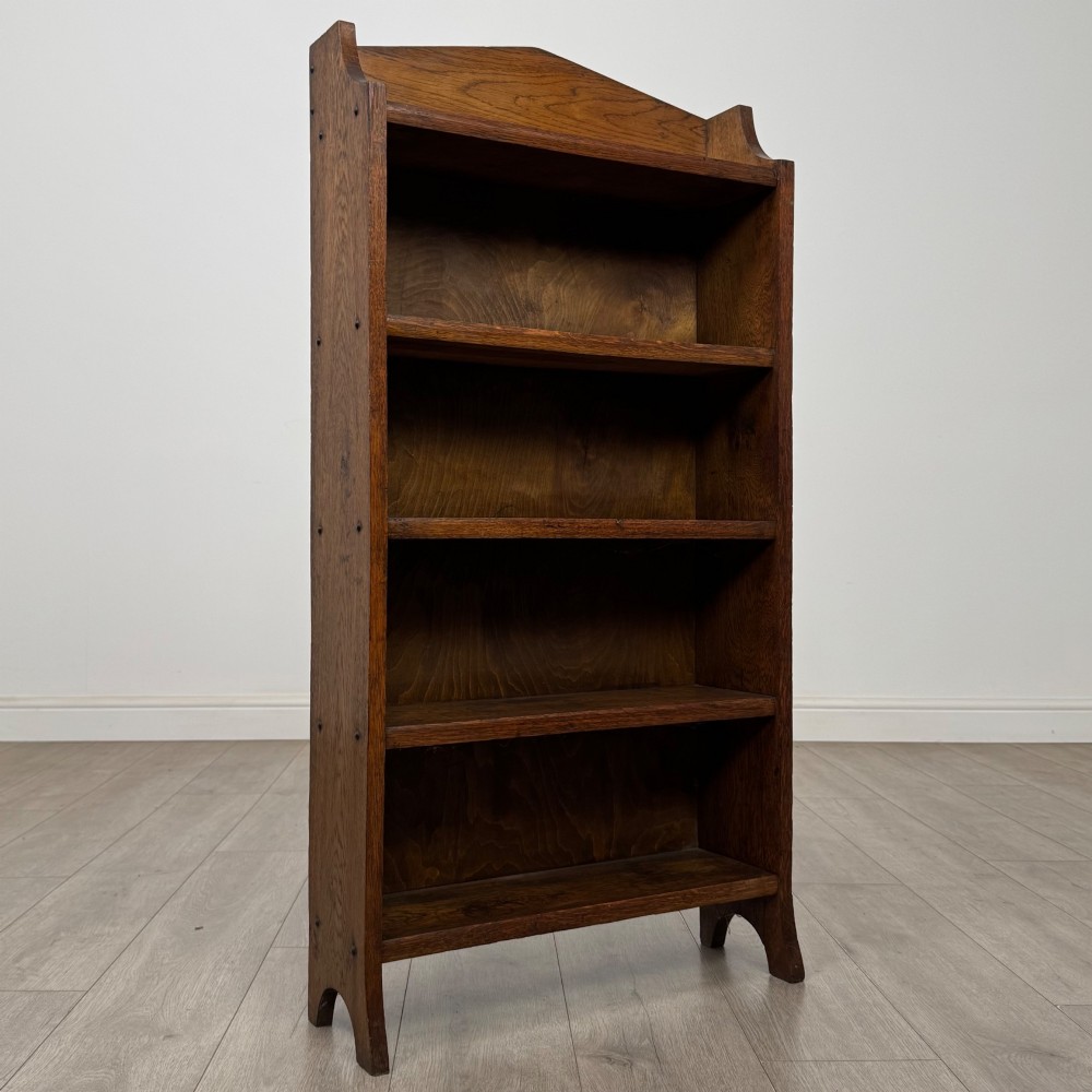 A freestanding Edwardian open oak bookcase featuring four tiers of shelves and a gabled top gallery. View IX