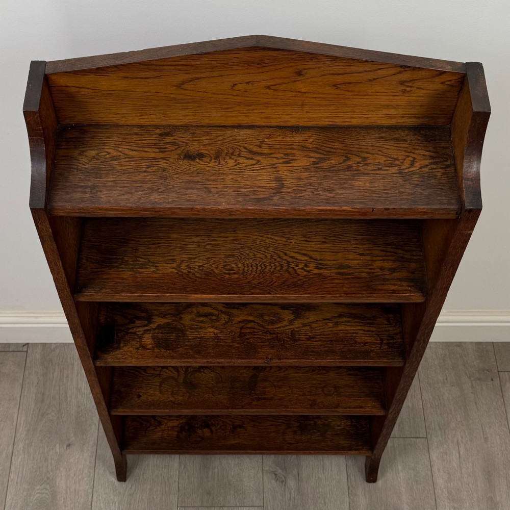A freestanding Edwardian open oak bookcase featuring four tiers of shelves and a gabled top gallery. View X