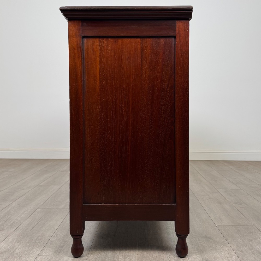 An antique Edwardian mahogany sideboard featuring two top drawers with brass drop handles above two field-panelled cupboard doors, resting on short turned feet. View IV
