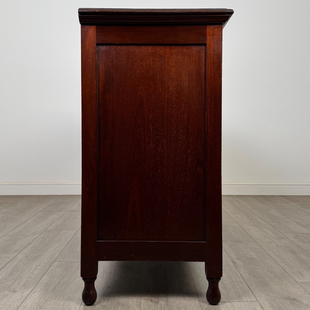 An antique Edwardian mahogany sideboard featuring two top drawers with brass drop handles above two field-panelled cupboard doors, resting on short turned feet. View VIII