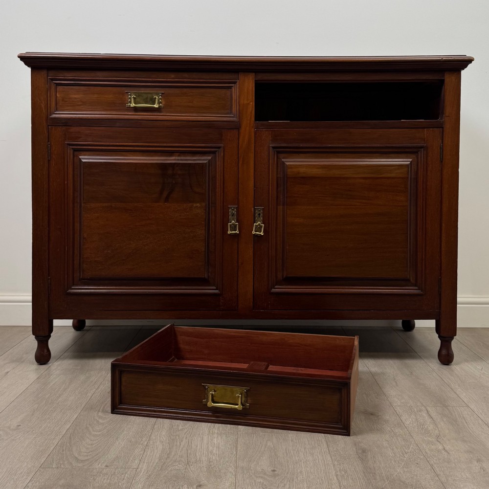 An antique Edwardian mahogany sideboard featuring two top drawers with brass drop handles above two field-panelled cupboard doors, resting on short turned feet. View XI