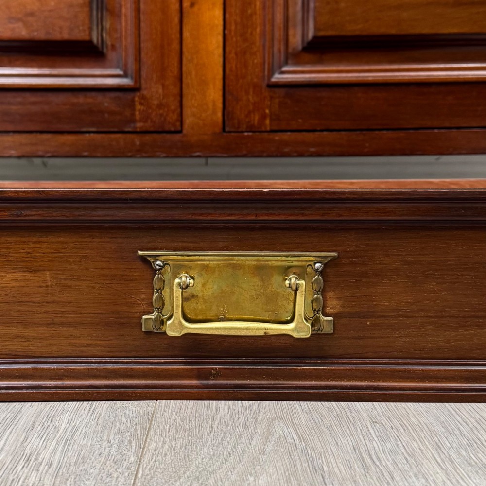 An antique Edwardian mahogany sideboard featuring two top drawers with brass drop handles above two field-panelled cupboard doors, resting on short turned feet. View XII