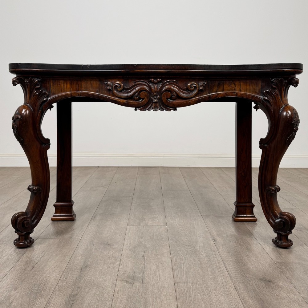 A 19th-century Victorian rosewood side table featuring hand-carved C-scroll ornament, a serpentine apron, and carved cabriole legs.