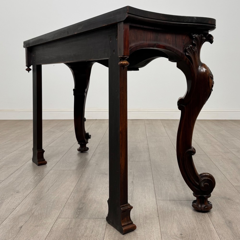 A 19th-century Victorian rosewood side table featuring hand-carved C-scroll ornament, a serpentine apron, and carved cabriole legs. View VI