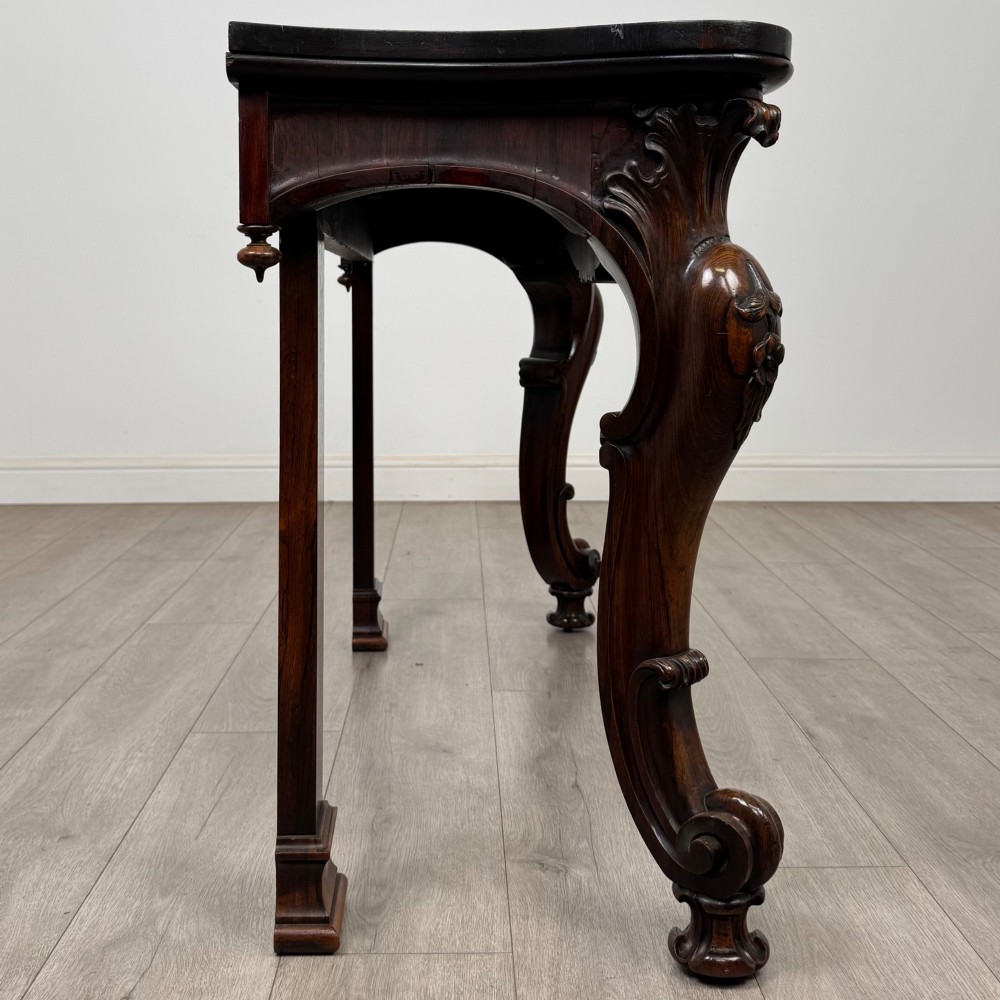 A 19th-century Victorian rosewood side table featuring hand-carved C-scroll ornament, a serpentine apron, and carved cabriole legs. View VII