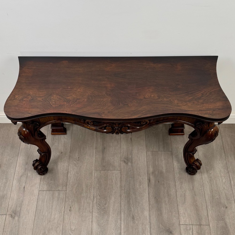 A 19th-century Victorian rosewood side table featuring hand-carved C-scroll ornament, a serpentine apron, and carved cabriole legs. View IX