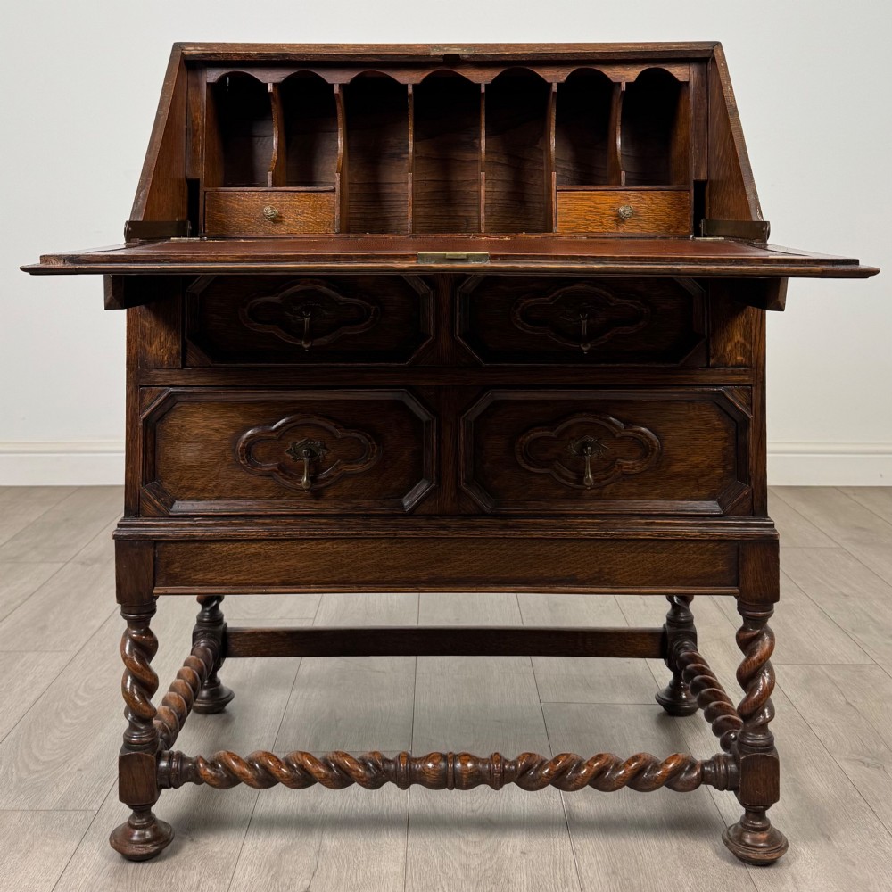 A dark oak Jacobean revival slant-front bureau featuring geometric panel mouldings, drop handles, and barley twist legs joined by stretchers. View II