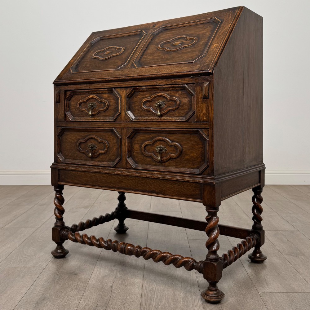 A dark oak Jacobean revival slant-front bureau featuring geometric panel mouldings, drop handles, and barley twist legs joined by stretchers. View III