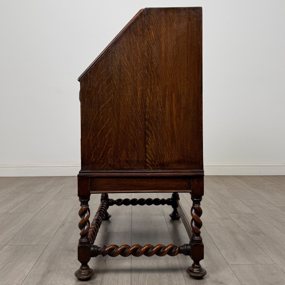 A dark oak Jacobean revival slant-front bureau featuring geometric panel mouldings, drop handles, and barley twist legs joined by stretchers. View IV