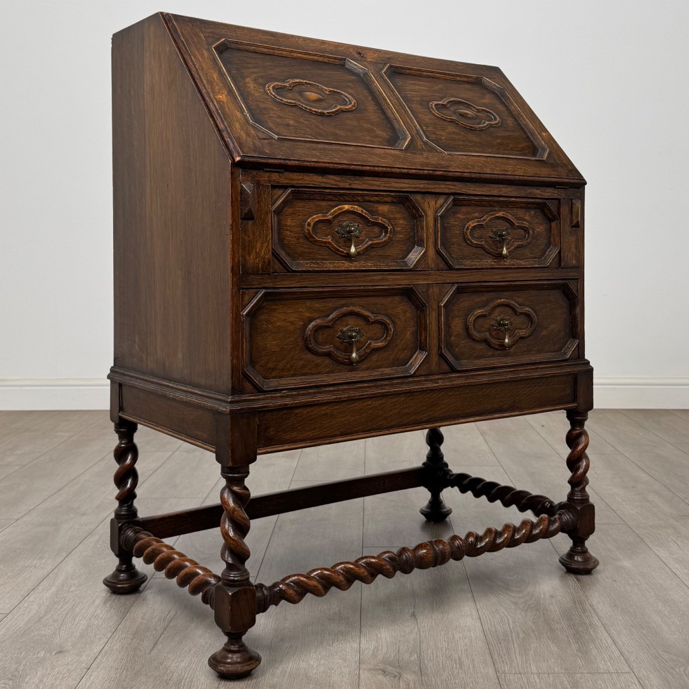 A dark oak Jacobean revival slant-front bureau featuring geometric panel mouldings, drop handles, and barley twist legs joined by stretchers. View IX