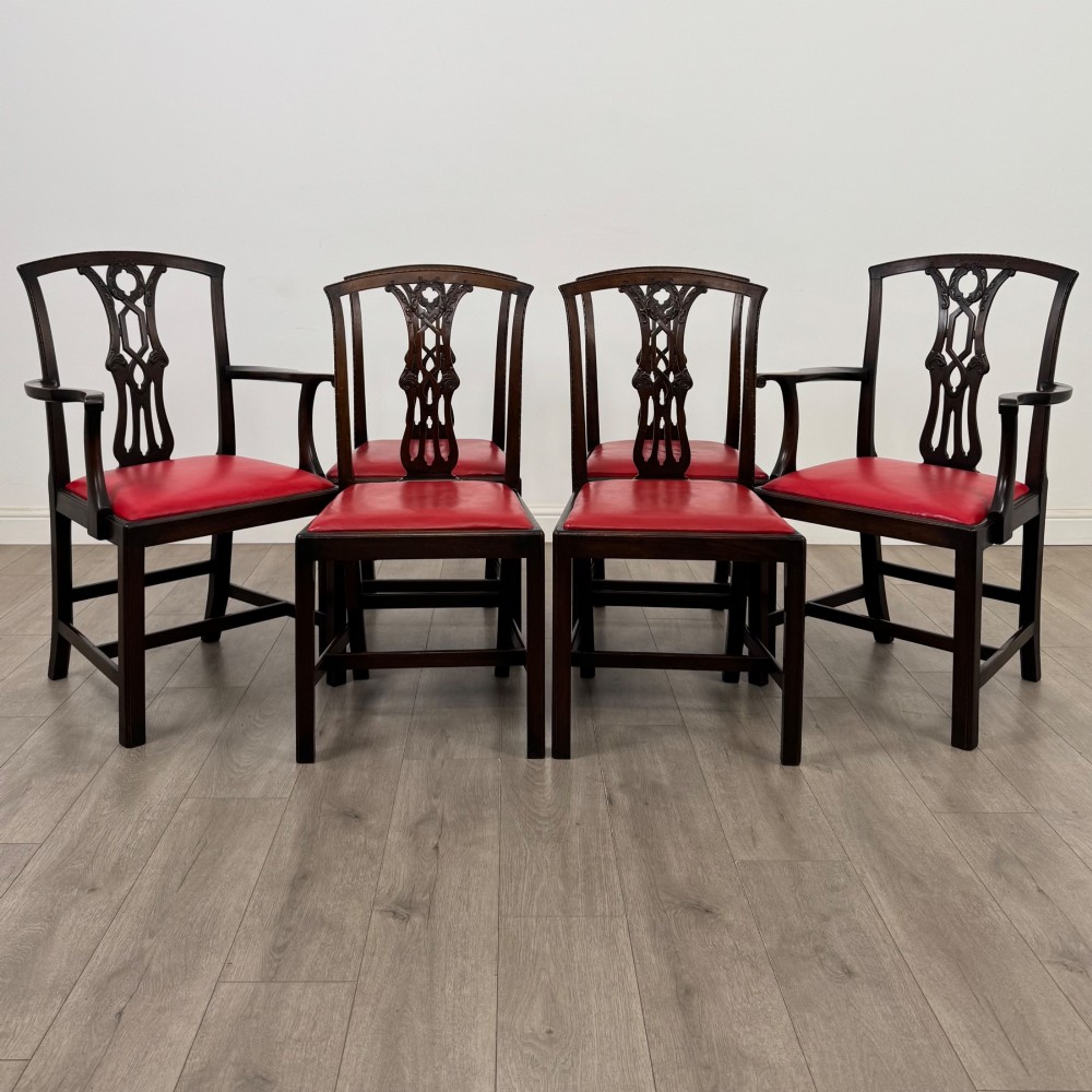 A set of six dark mahogany Georgian dining chairs featuring pierced back splats, straight legs with stretchers, and bright red leather drop-in seats.