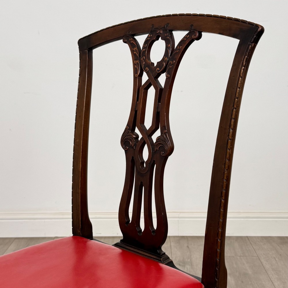 A set of six dark mahogany Georgian dining chairs featuring pierced back splats, straight legs with stretchers, and bright red leather drop-in seats. View V